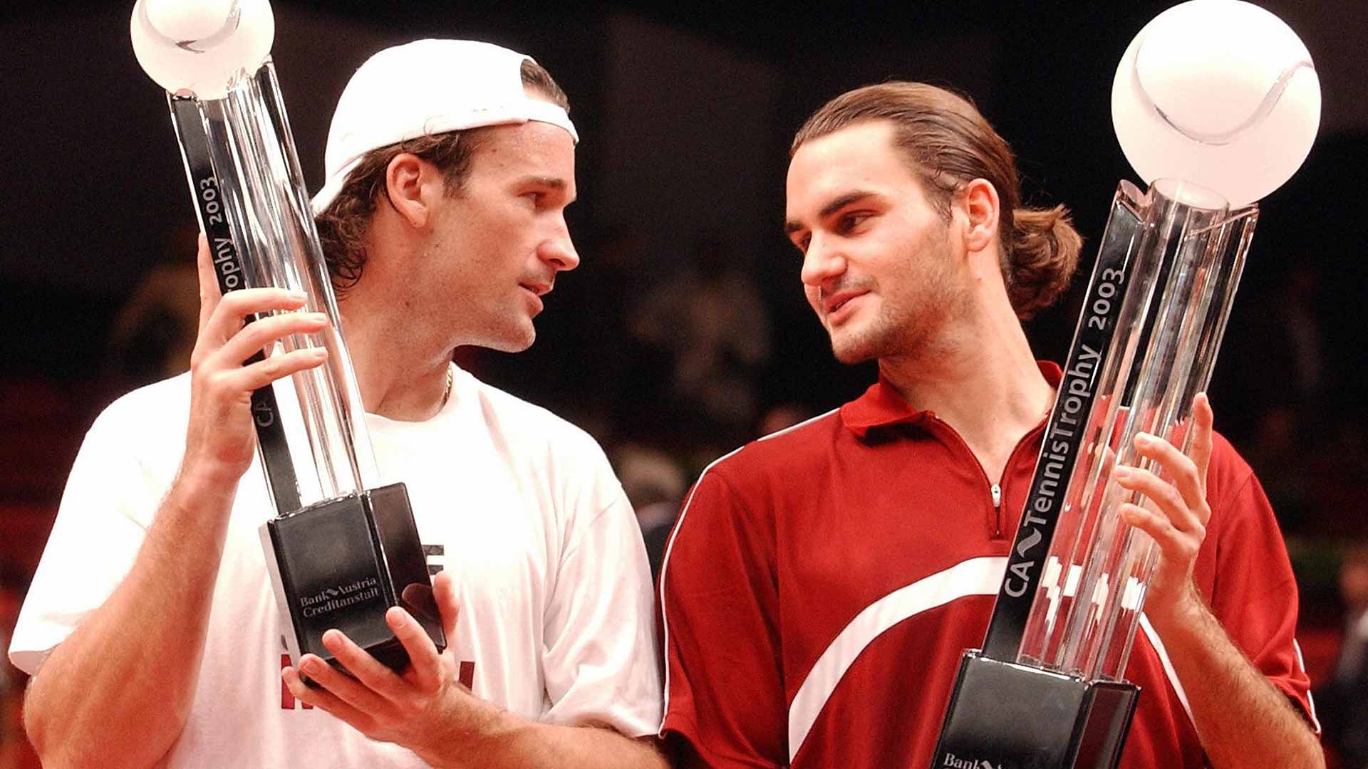 <a href='https://www.atptour.com/en/players/carlos-moya/m605/overview'>Carlos Moya</a> and winner <a href='https://www.atptour.com/en/players/roger-federer/f324/overview'>Roger Federer</a> display their trophies following the 2003 Vienna final