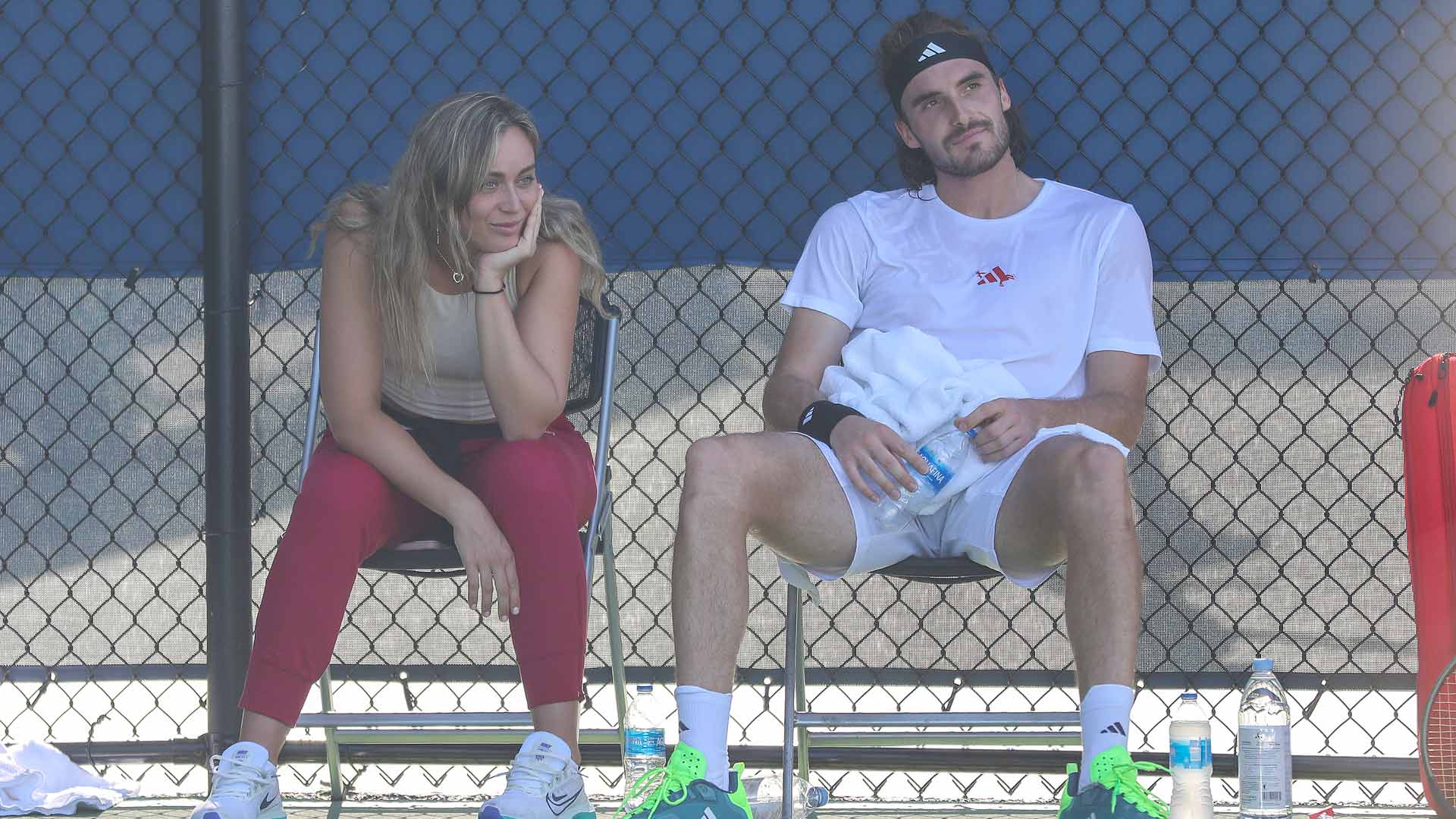 Paula Badosa and Stefanos Tsitsipas sit in the shade during Tsitsipas' Saturday practice with Grigor Dimitrov.