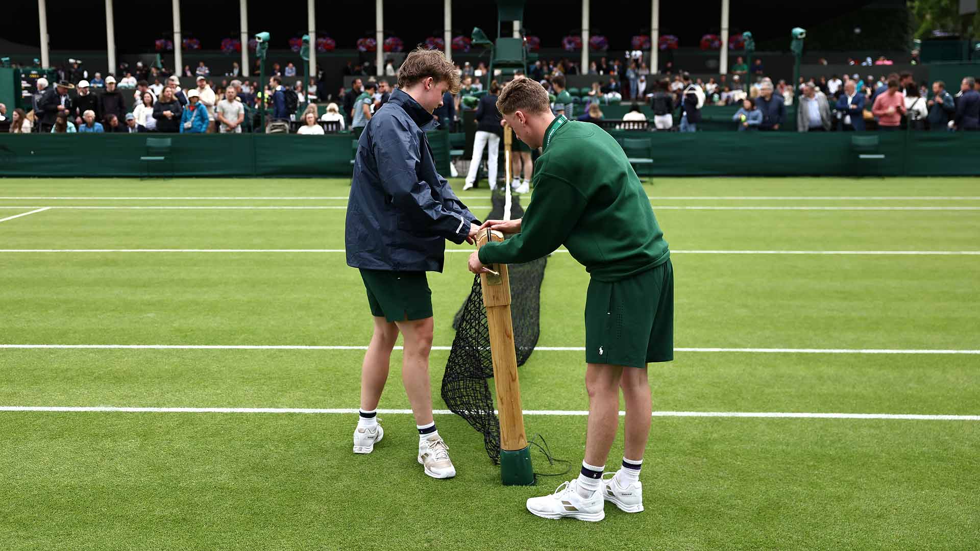 Ground staff put the nets back on court at Wimbledon after rain.