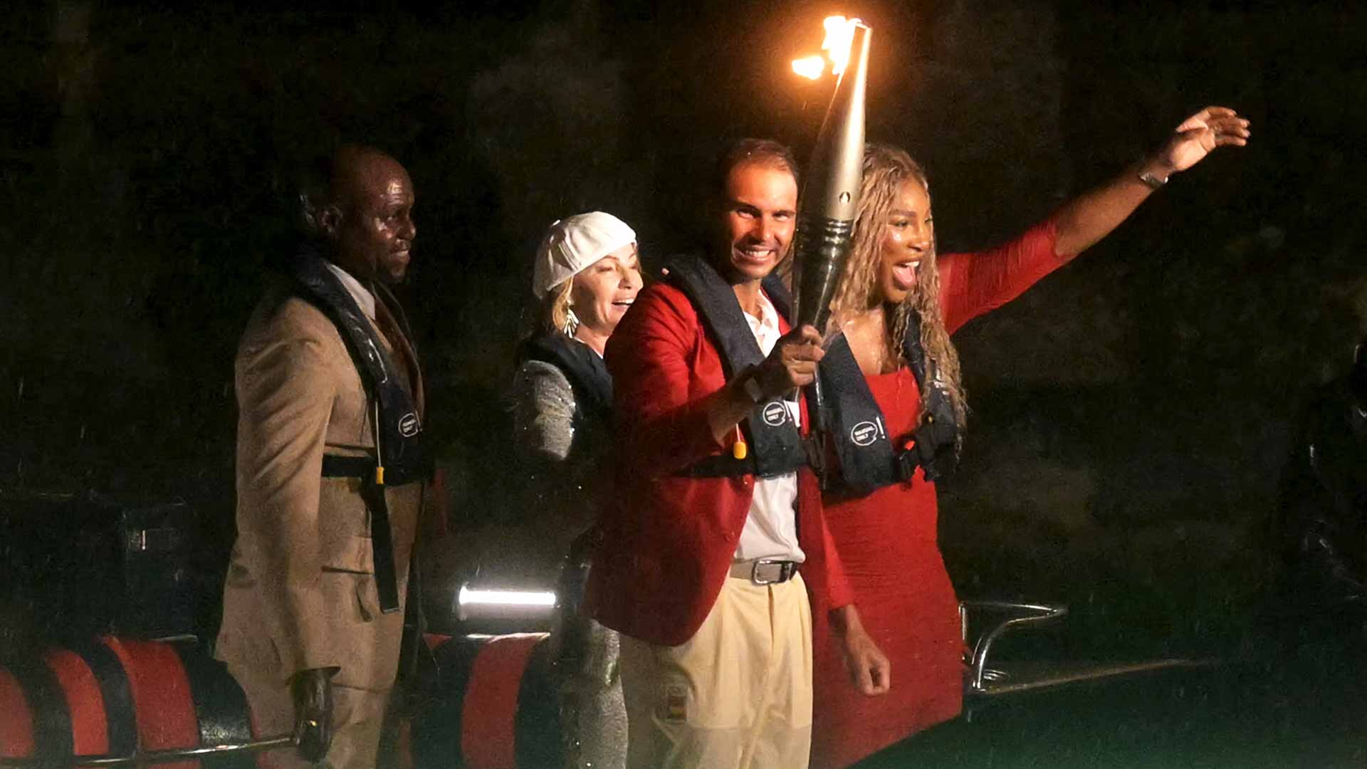 Rafael Nadal carries to Olympic torch on a boat on the Seine River alongside Serena Williams, Carl Lewis and Nadia Comaneci.
