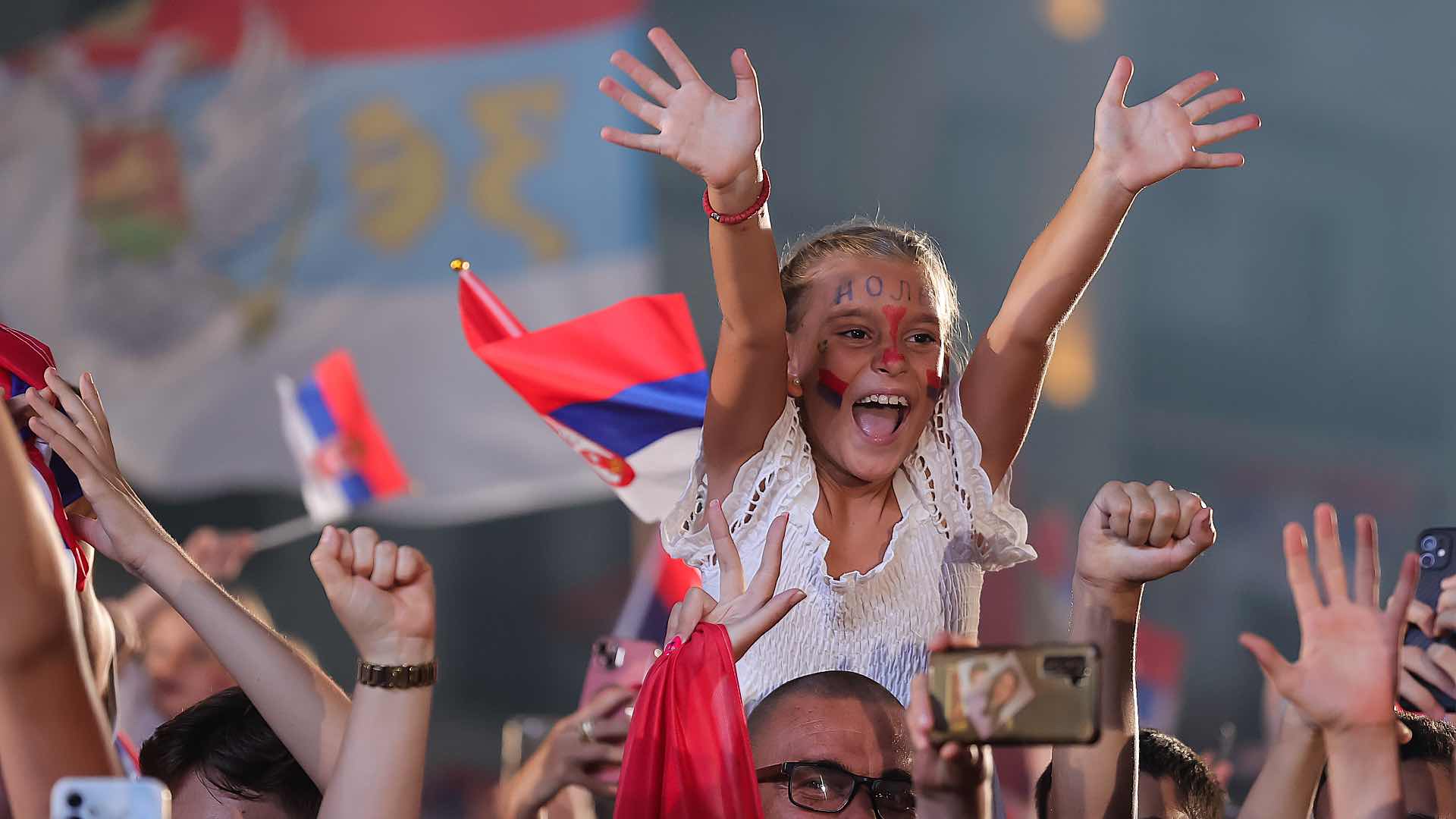 A young Serbian fan cheers for Djokovic and his fellow Serbian athletes.